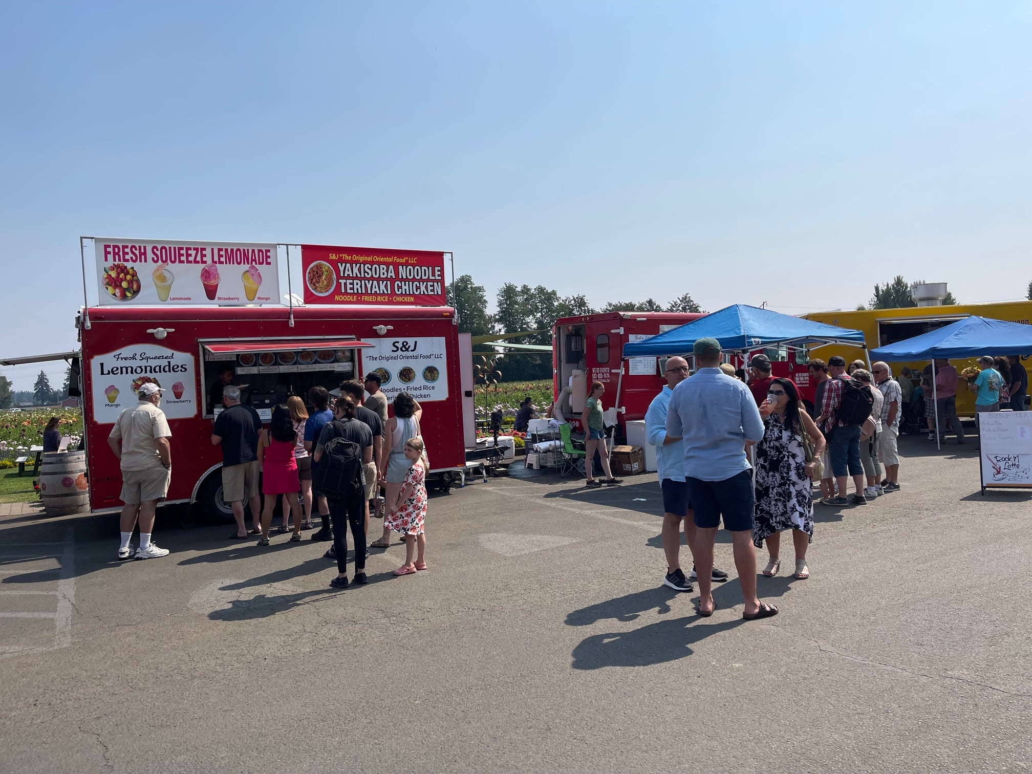 Attendees gather around food trucks on a sunny day at the farm